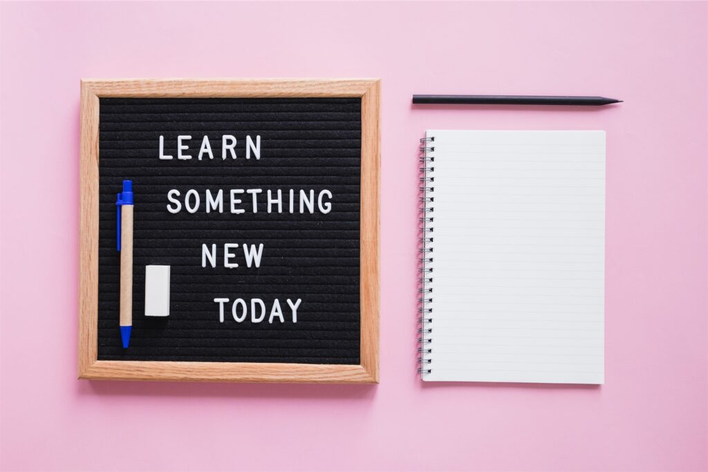 The picture shows a writing board on which is written: "Learn something new today". Next to it is a writing pad and a pen. Jumpstart Your Corporate Learning in 2023!
