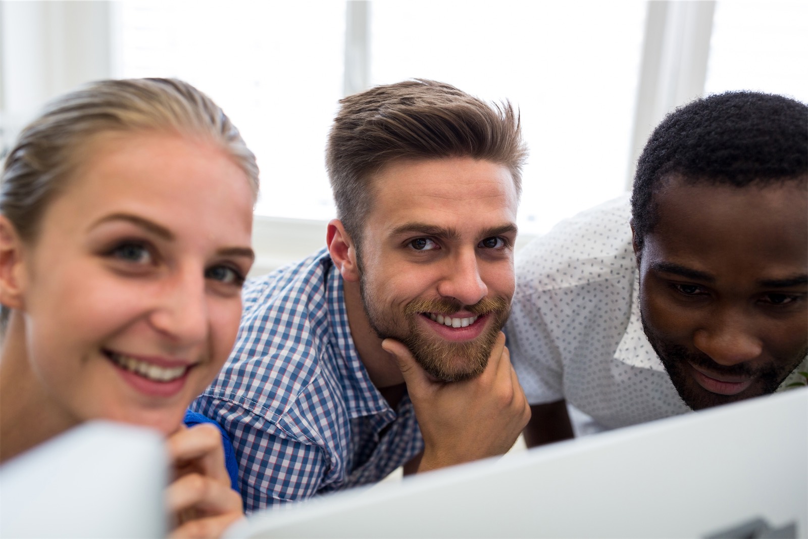 The image shows a group of graphic designers smiling while working on computer. Transform your business with a Learning Experience Platform.