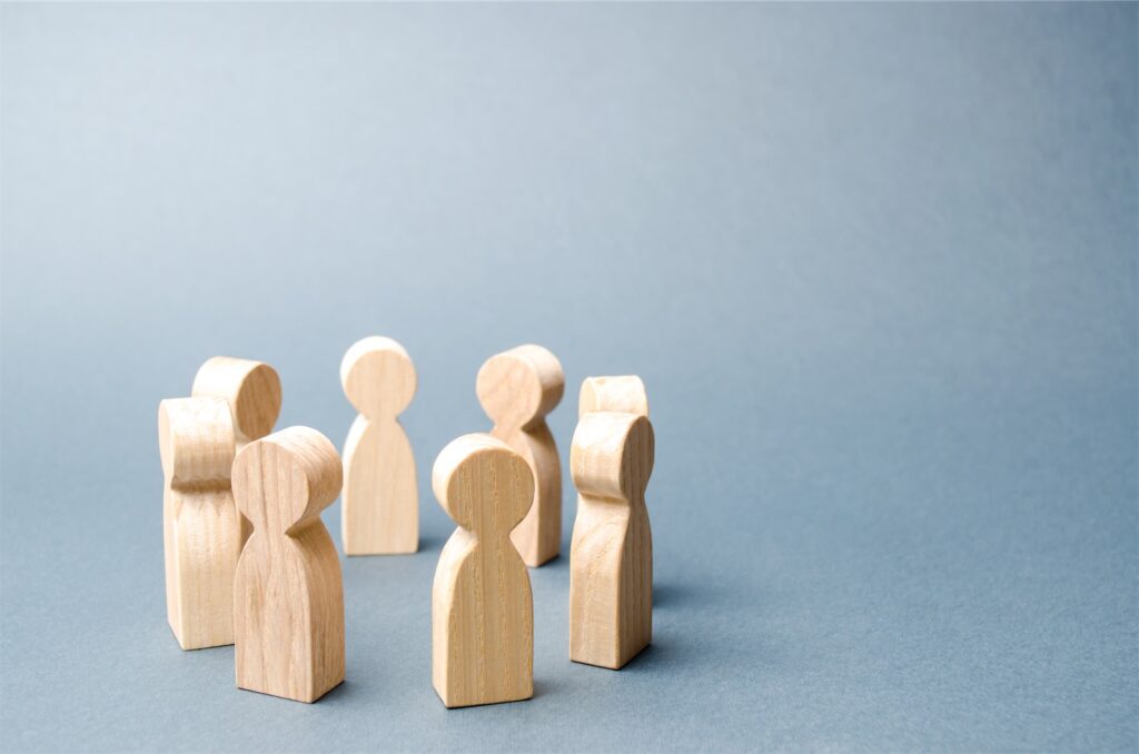 The picture shows wooden figures in a circle and symbolizes the good cooperation in sales teams. Transform your Sales Team with technology!